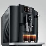 Jura E6 Piano Black mit zwei Espressi in Seitenansicht – erhältlich bei Caffista