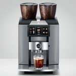 JURA GIGA W10 mit zwei Bohnenbehältern und einem Glas in der Frontansicht