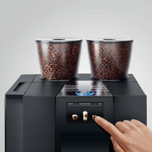 Finger tippt auf Bohnenwahltaste der GIGA X8 mit zwei Bohnenbehältern