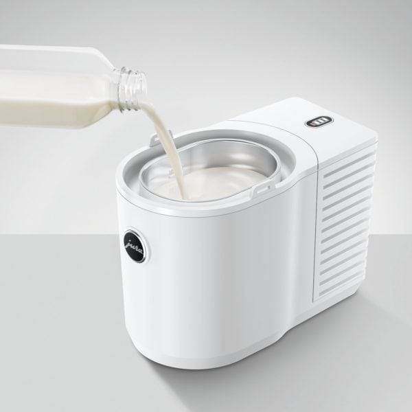 Frische Milch wird in den Jura Cool Control Weiß gegossen