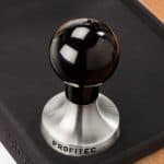 Profitec Tamper auf schwarzer Tampermatte in Barista-Umgebung